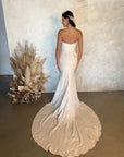 Back view of the Aveline fitted strapless wedding dress with covered buttons and a floral appliqué train