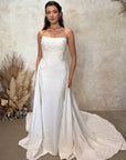 Front view of the Aveline fitted strapless wedding dress with floral lace appliqué and detachable draped train panels