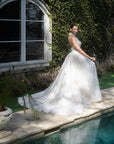 Three-quarter back view of the Evangeline lace A-line wedding dress with a detachable topper and flowing train