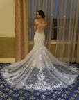 Back view of the Léonie Gown, a fitted lace mermaid wedding dress with illusion details and a dramatic floral lace cathedral train.