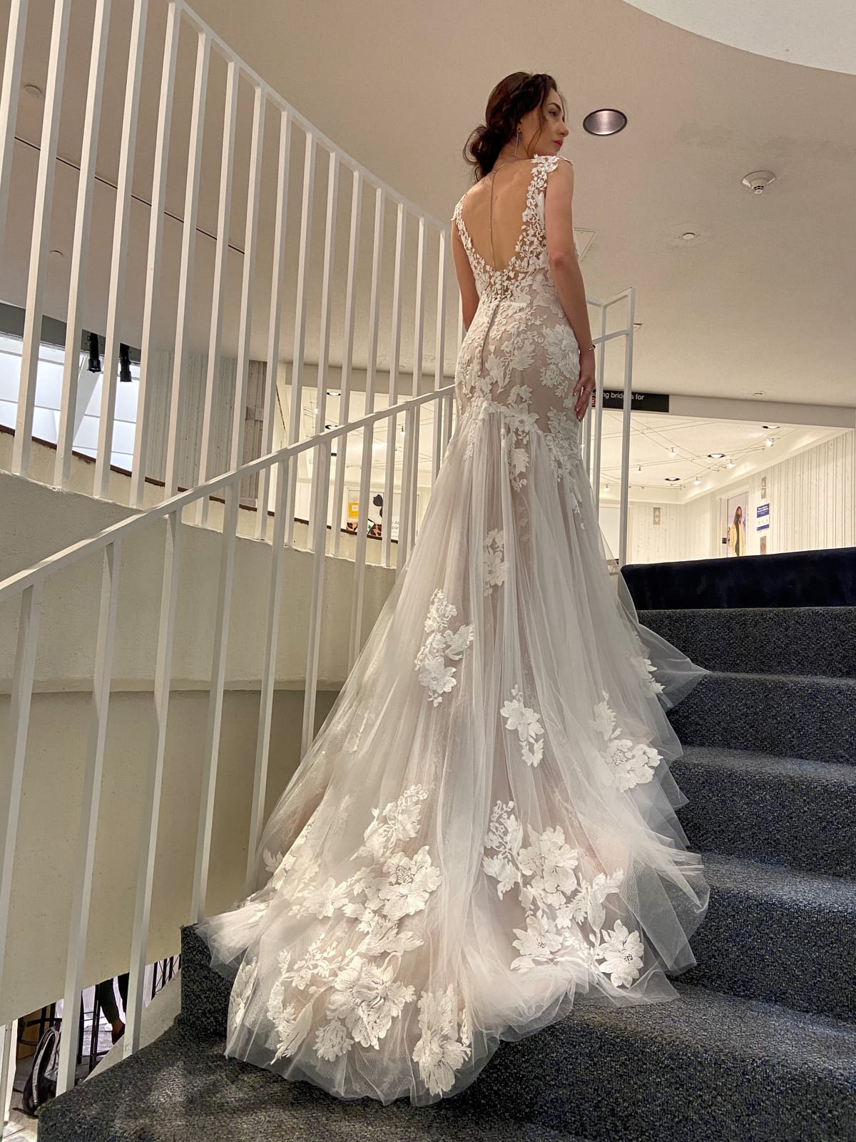 Back view of Amélie fit-and-flare wedding gown featuring a low scoop back, floral lace appliqué and sweeping tulle train.