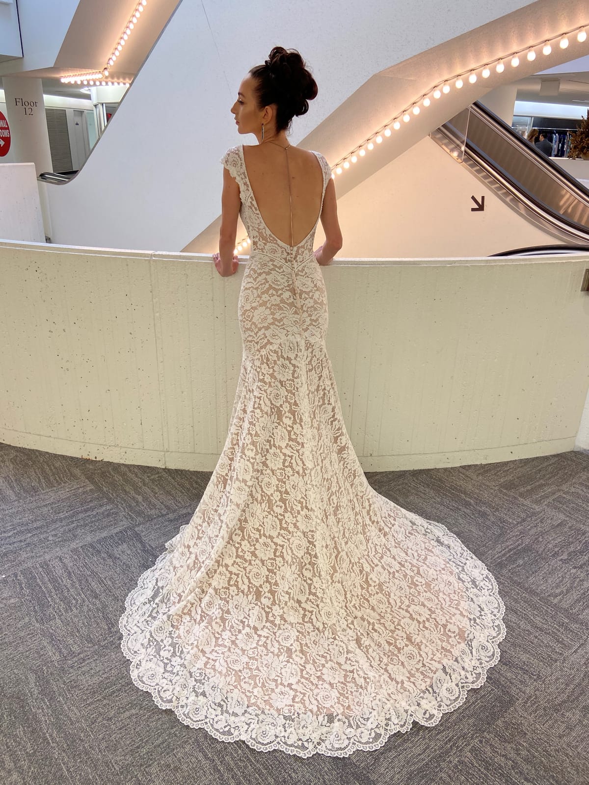 Back view of the Amélie lace wedding gown featuring a low V-back and sweeping scalloped lace train.