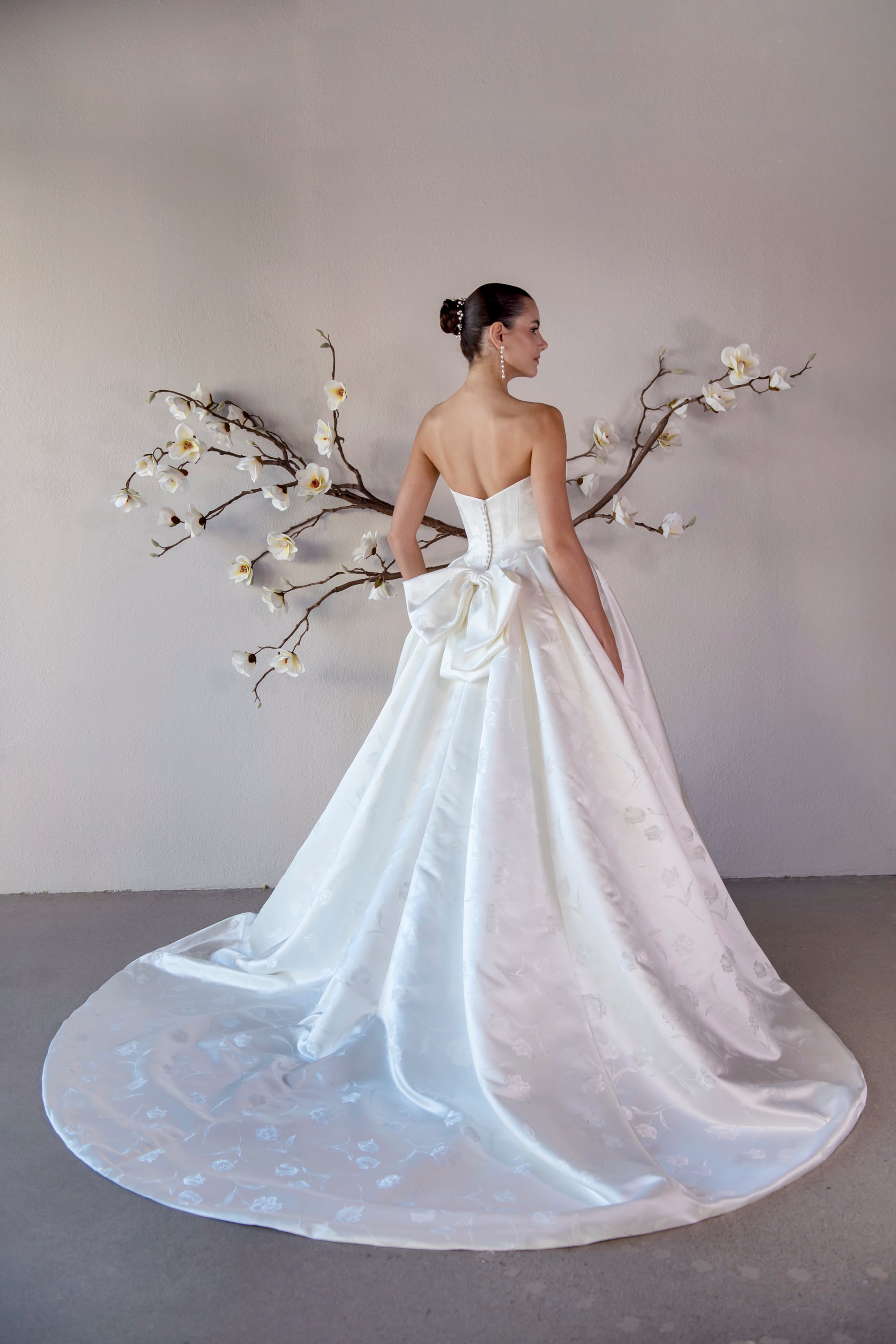 Three-quarter back view of the Le Nœud strapless ball gown with a detachable bow and voluminous train