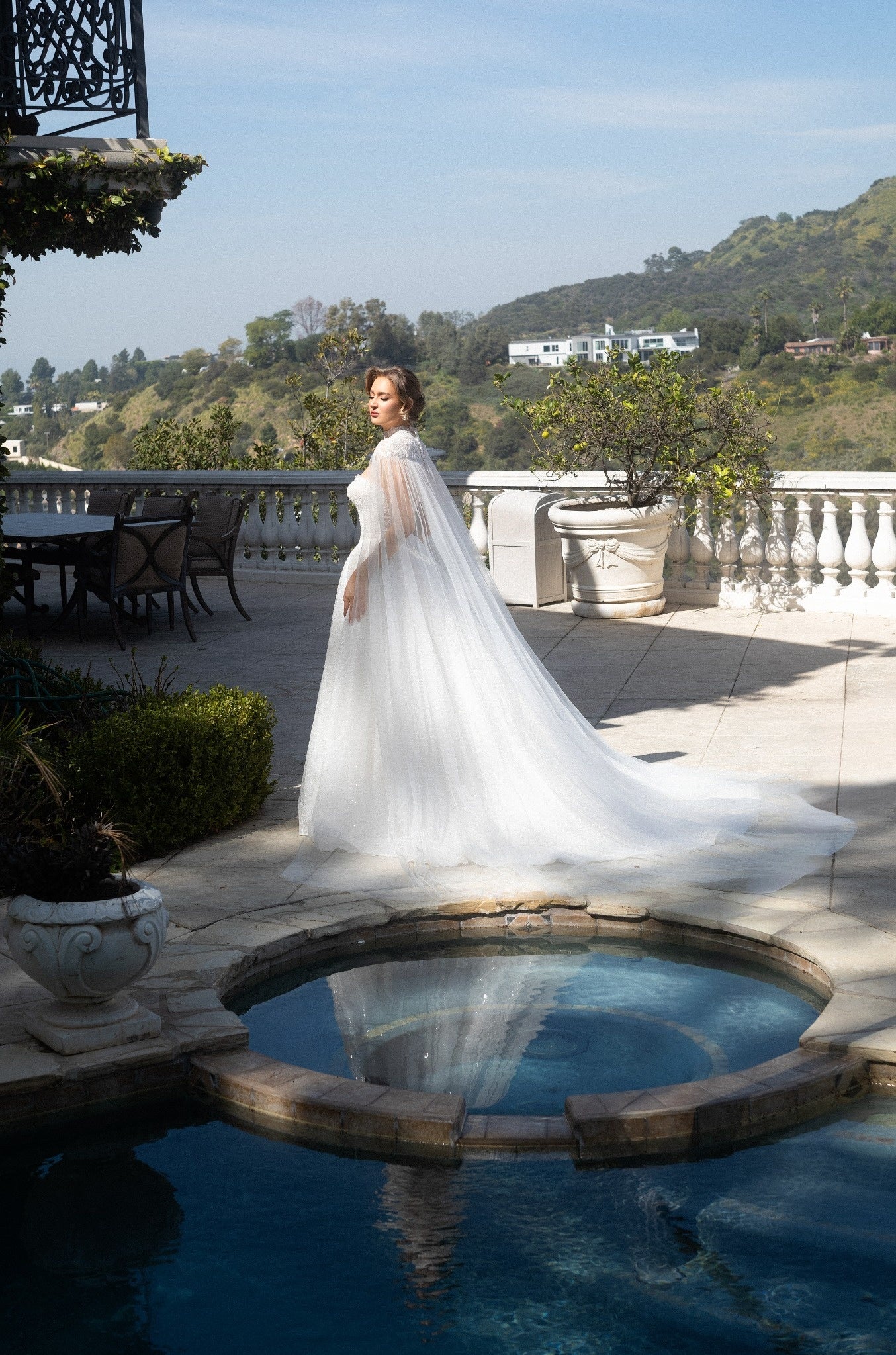 Side view of the Aurelia beaded ball gown styled with a detachable sheer tulle bridal cape and flowing train