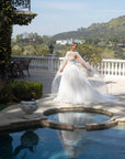 Front view of the Aurelia beaded French lace ball gown styled with a high-neck detachable bridal cape