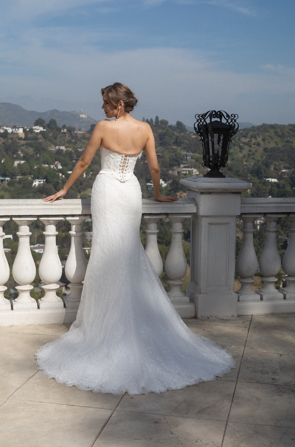 Back view of the Aurelia fitted lace wedding dress with a lace-up corset and flowing lace train