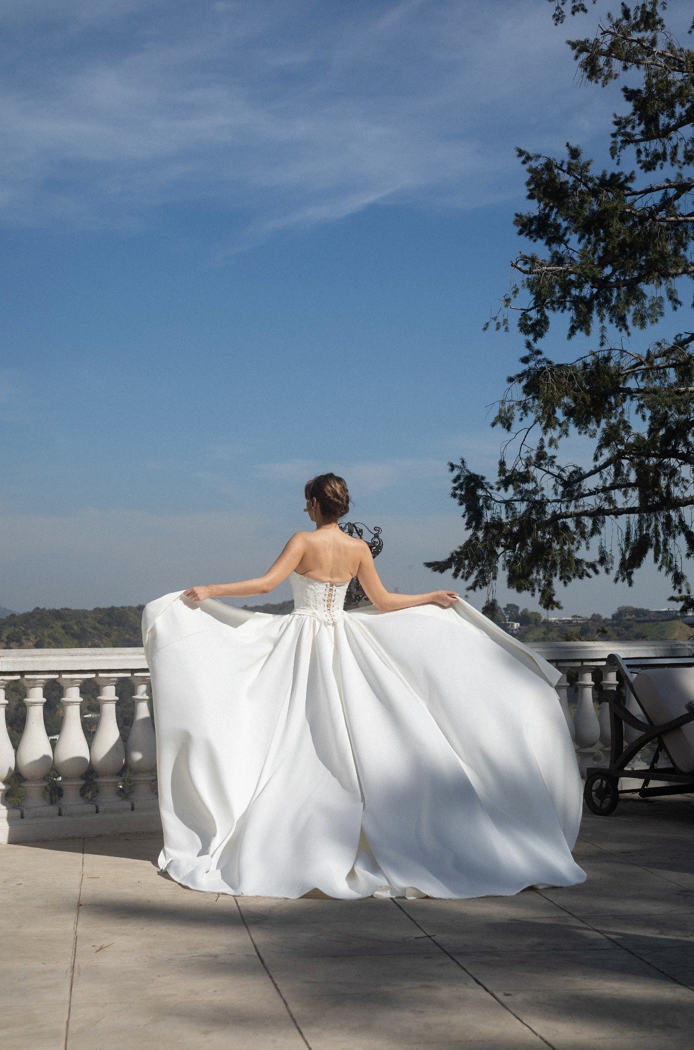 Back view of the Aurelia fitted wedding dress with two detachable train panels held open to show their full volume