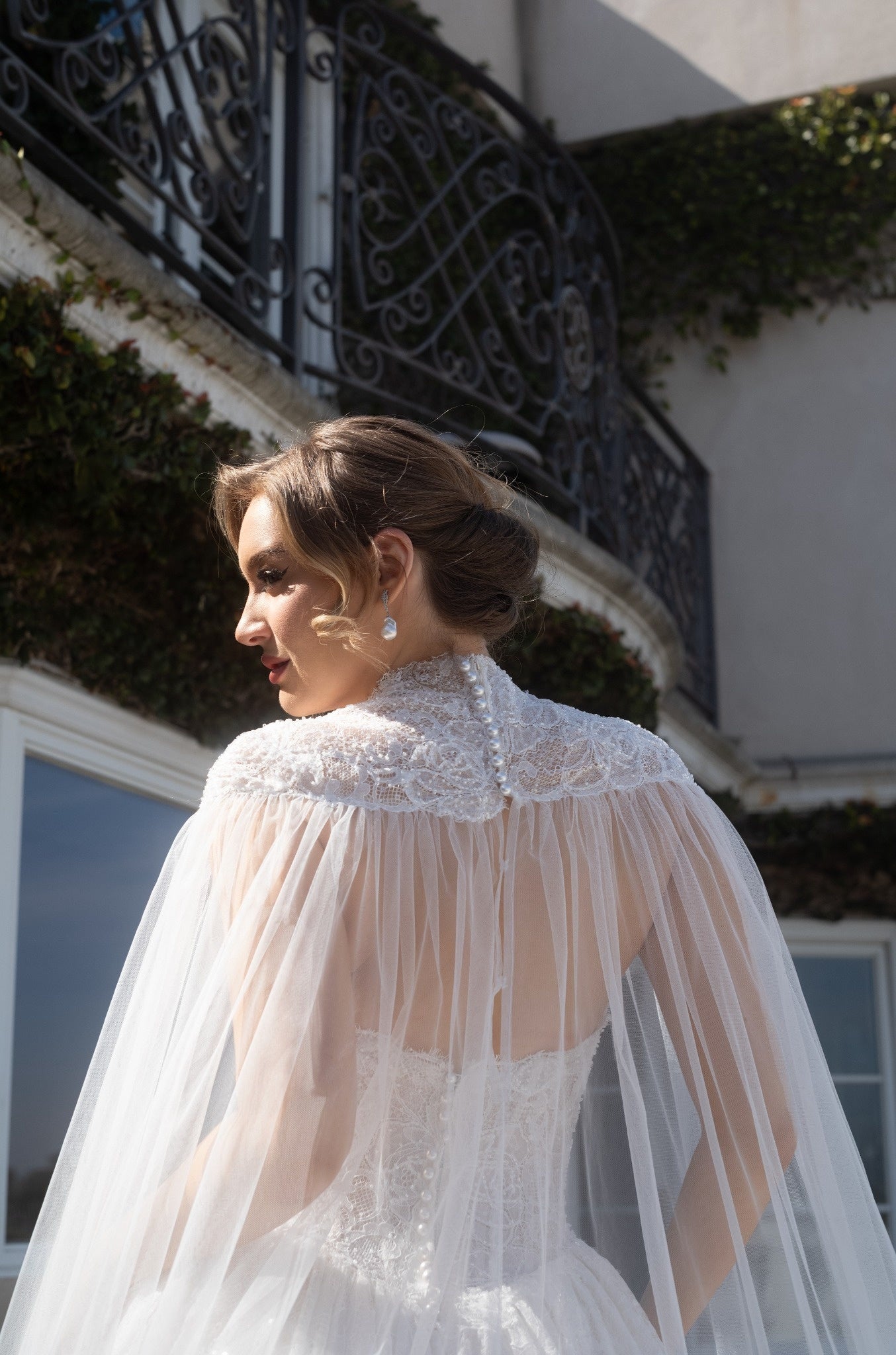 Back neckline detail of the Aurelia detachable bridal cape with French lace, pearl-style buttons, and sheer tulle