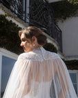 Back neckline detail of the Aurelia detachable bridal cape with French lace, pearl-style buttons, and sheer tulle