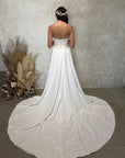 Back view of the Aveline fitted strapless wedding dress with floral lace appliqué and detachable draped train panels