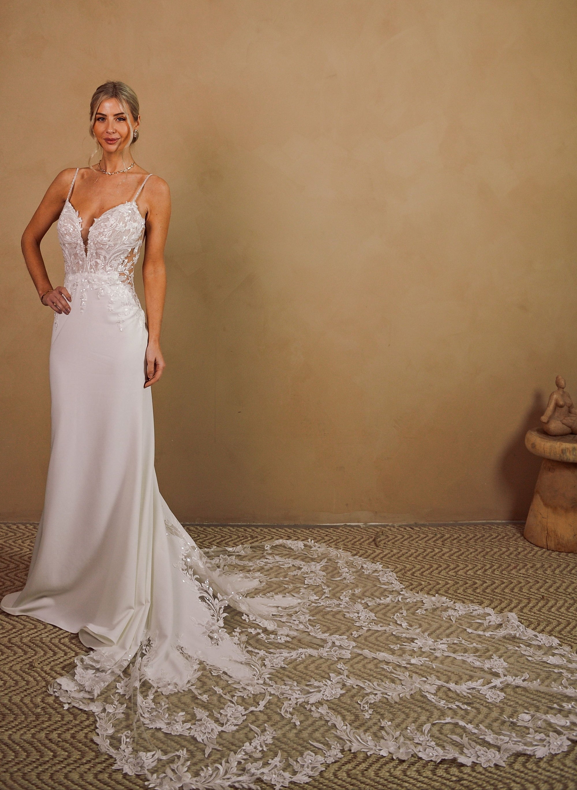 Elara clean fitted wedding dress with plunging neckline and dramatic floral lace train at Swan Bridal