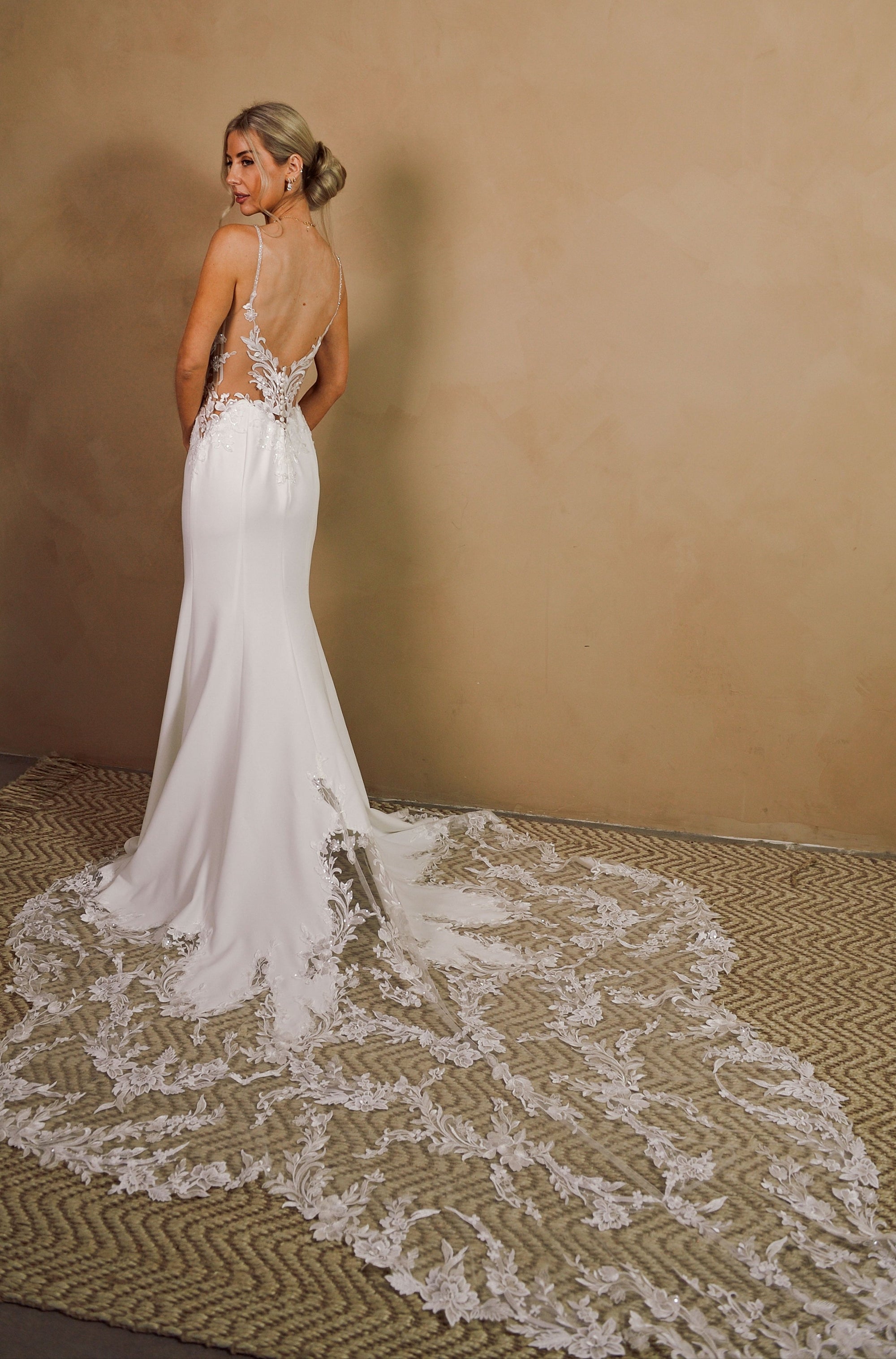 Back view of the Elara open back fitted wedding dress with floral lace appliqué and dramatic lace train