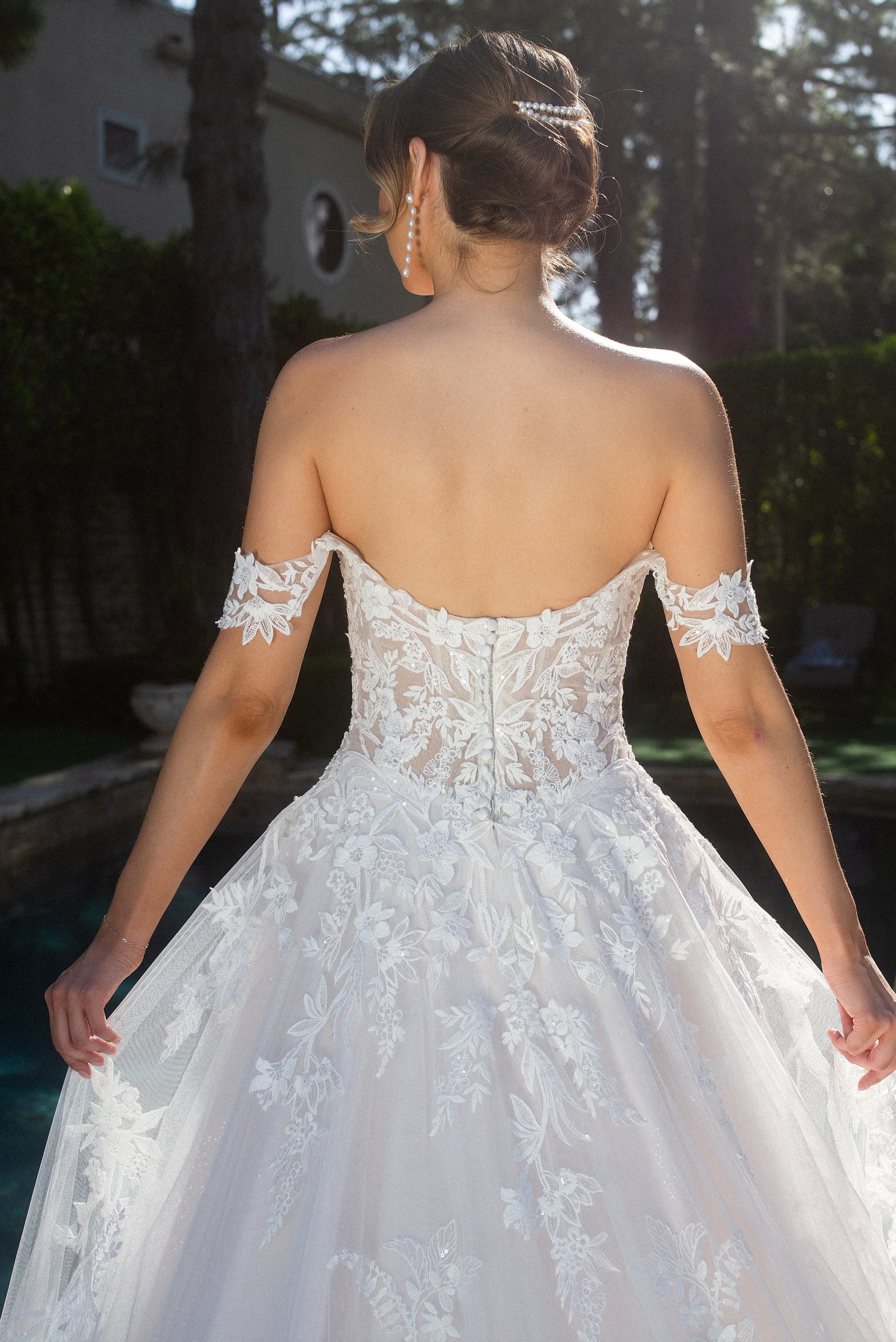Back bodice detail of the Elaria lace ball gown with a low scoop back, covered buttons, and 3D floral appliqué