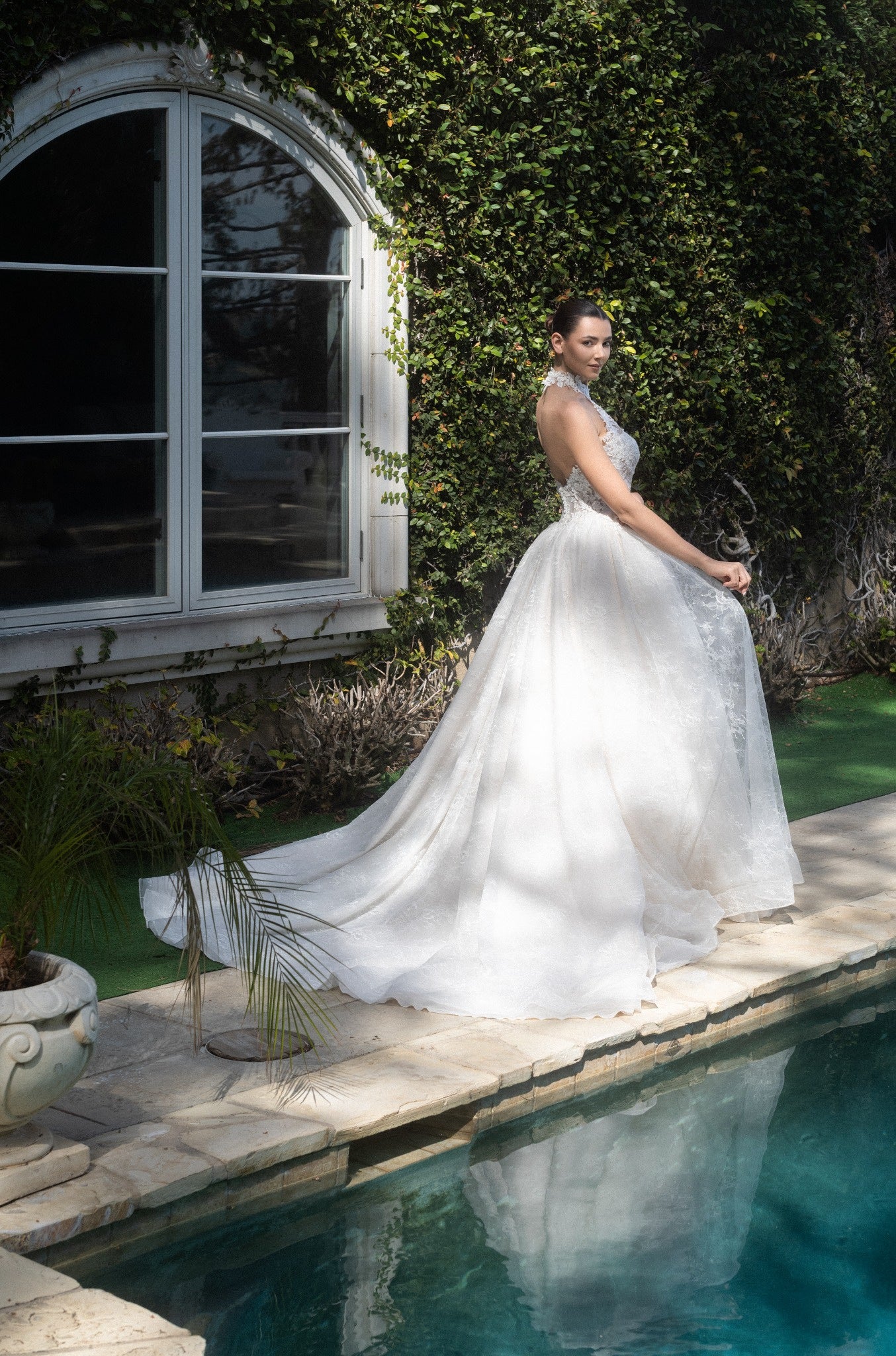 Three-quarter back view of the Evangeline lace A-line wedding dress with a detachable topper and flowing train