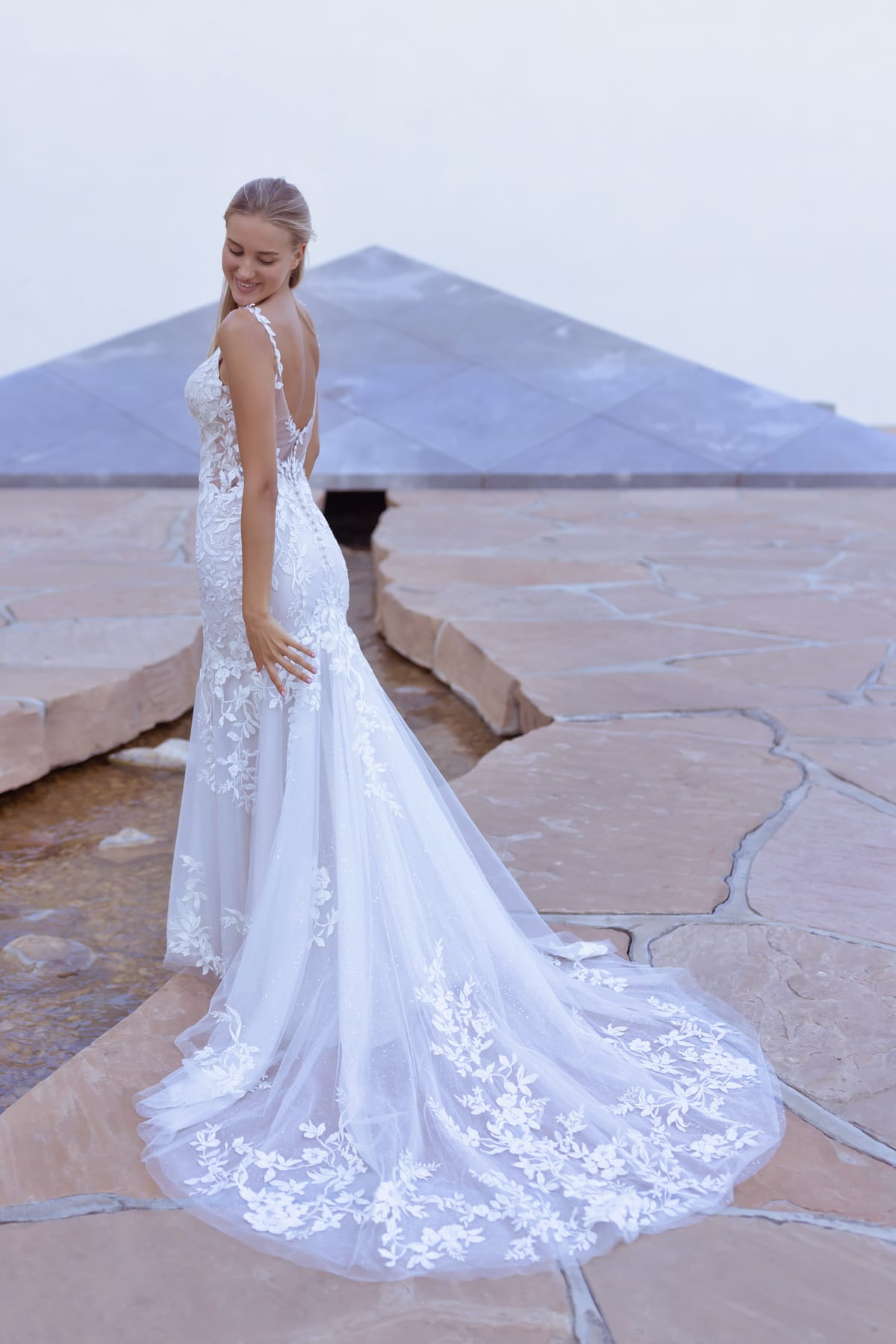 Back view of the Florienne Gown featuring a low open back and sweeping floral lace wedding dress train.