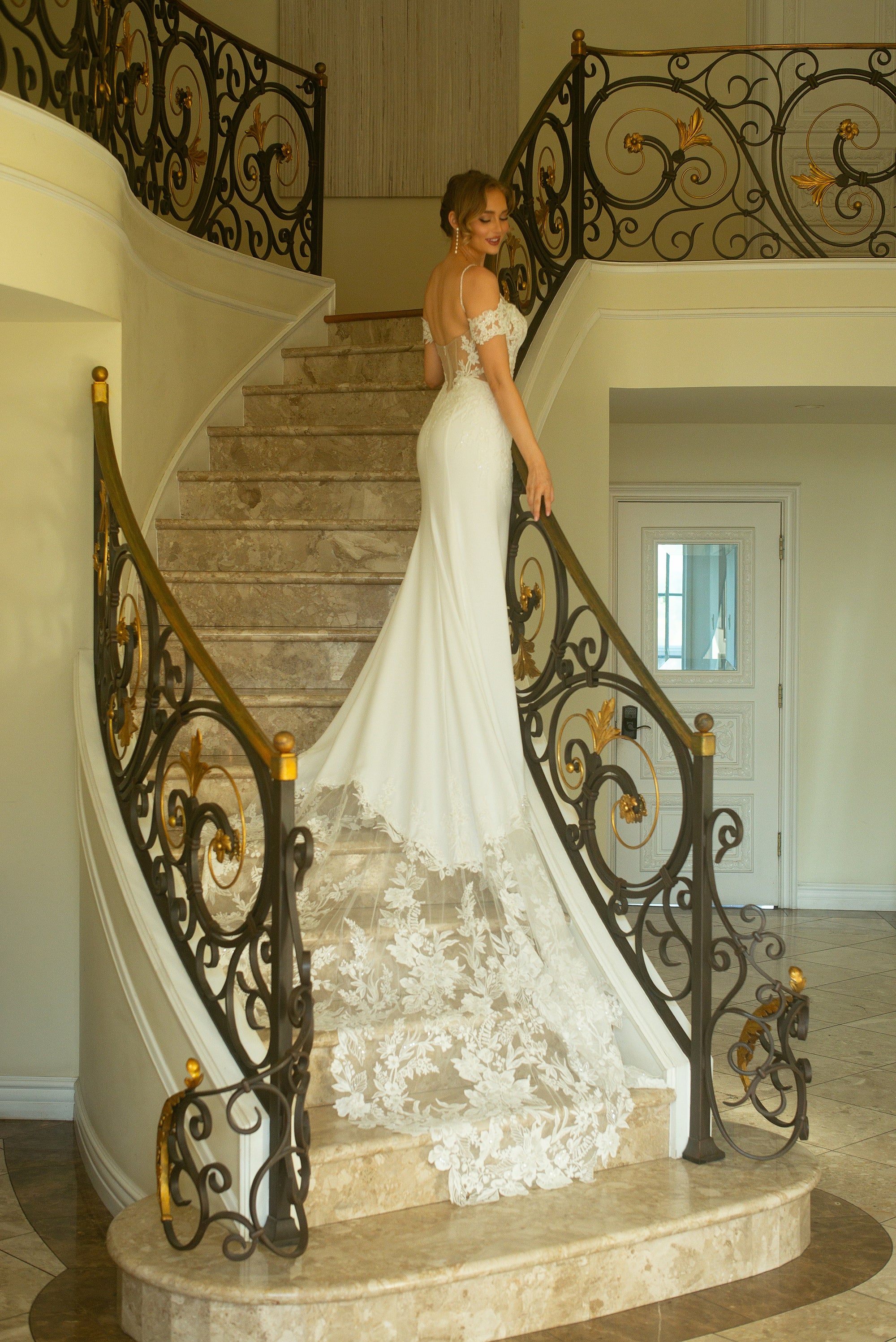Three-quarter back view of the Giardino fitted crepe wedding dress with off-the-shoulder lace sleeves and a dramatic floral lace train
