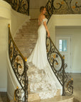 Three-quarter back view of the Giardino fitted crepe wedding dress with off-the-shoulder lace sleeves and a dramatic floral lace train