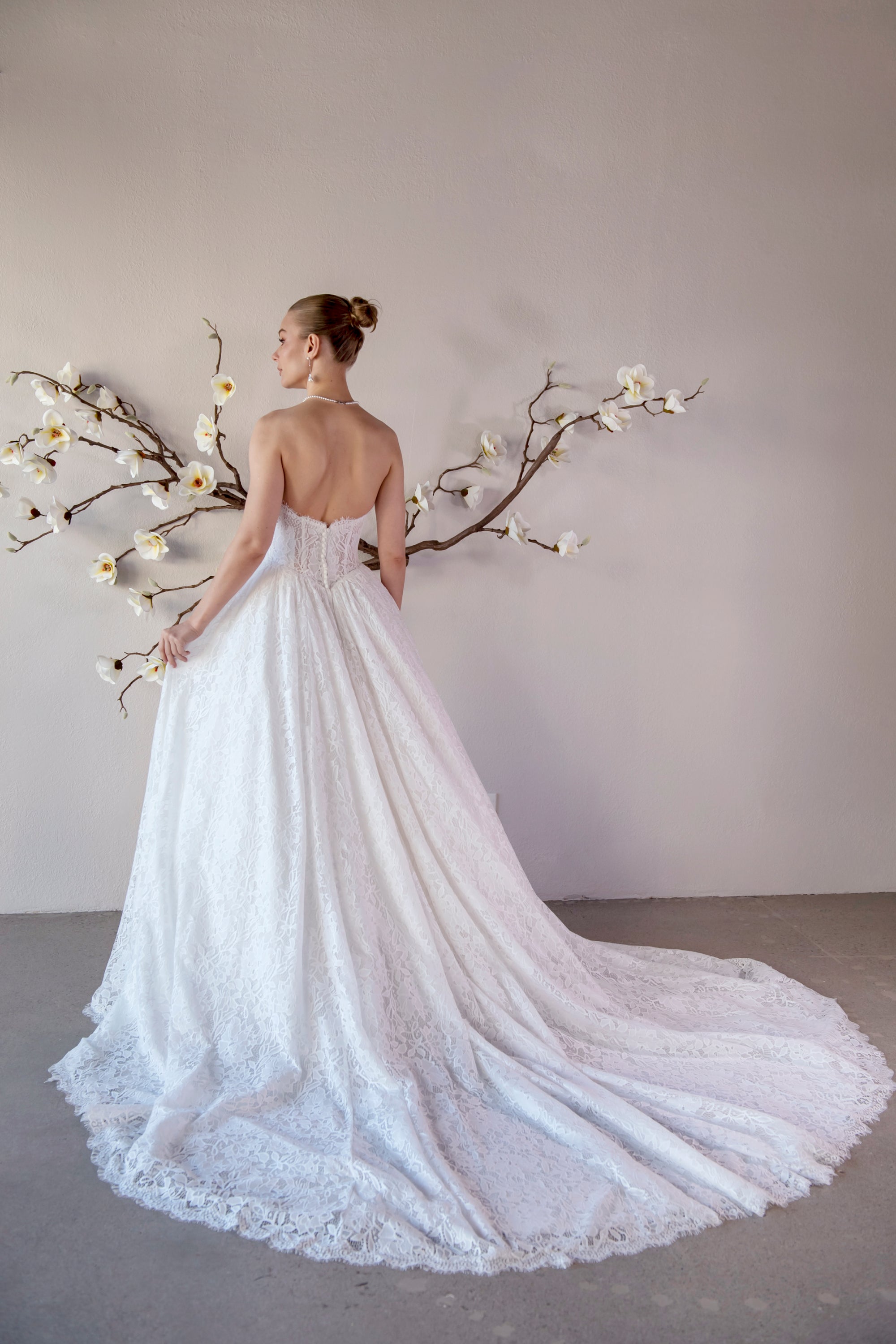 Back view of the Isolde lace ball gown with a low scoop back, covered buttons, and sweeping lace train