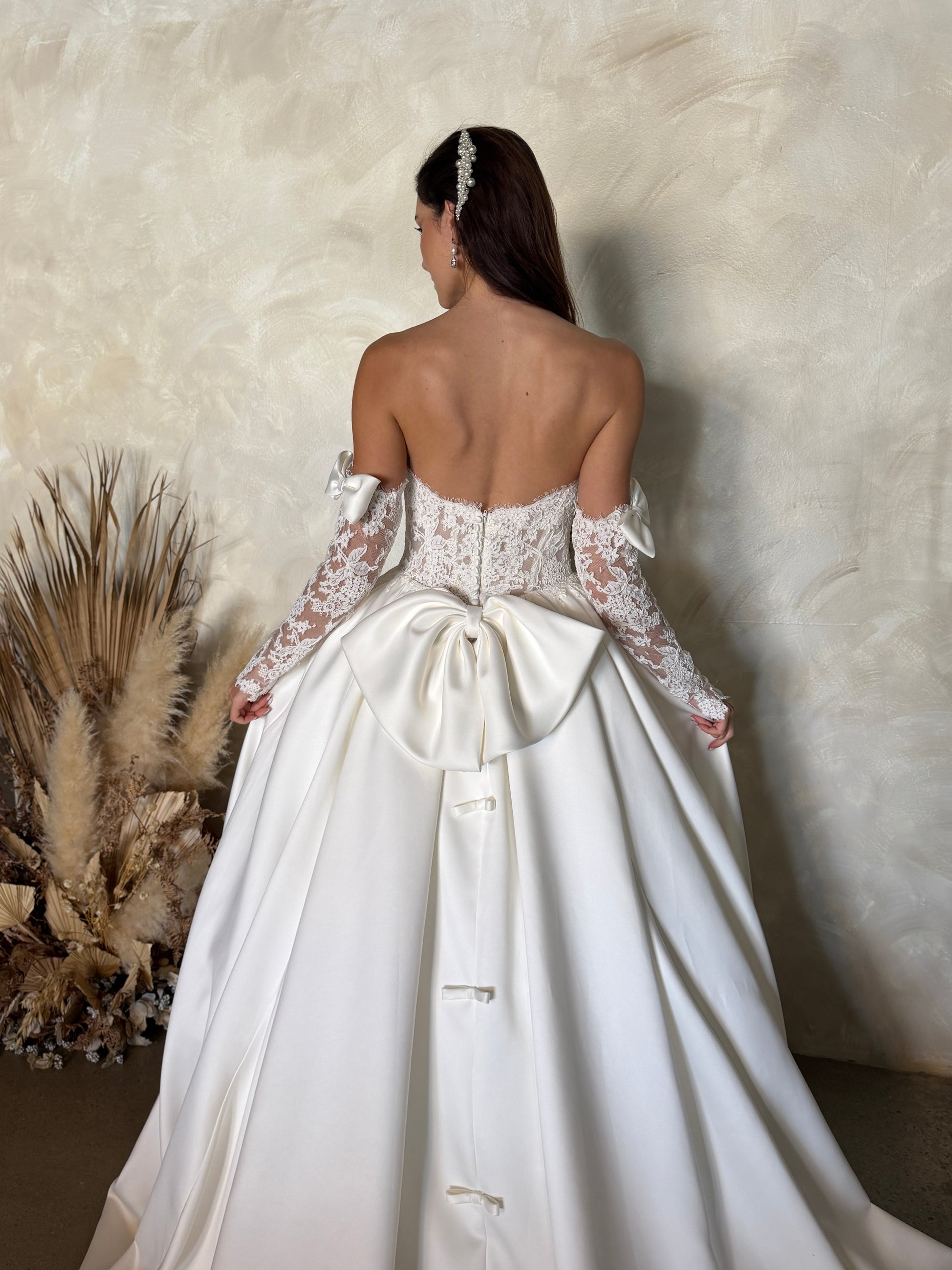 Back detail of the Marcelline ball gown with an oversized detachable bow, French lace bodice, and petite bow accents