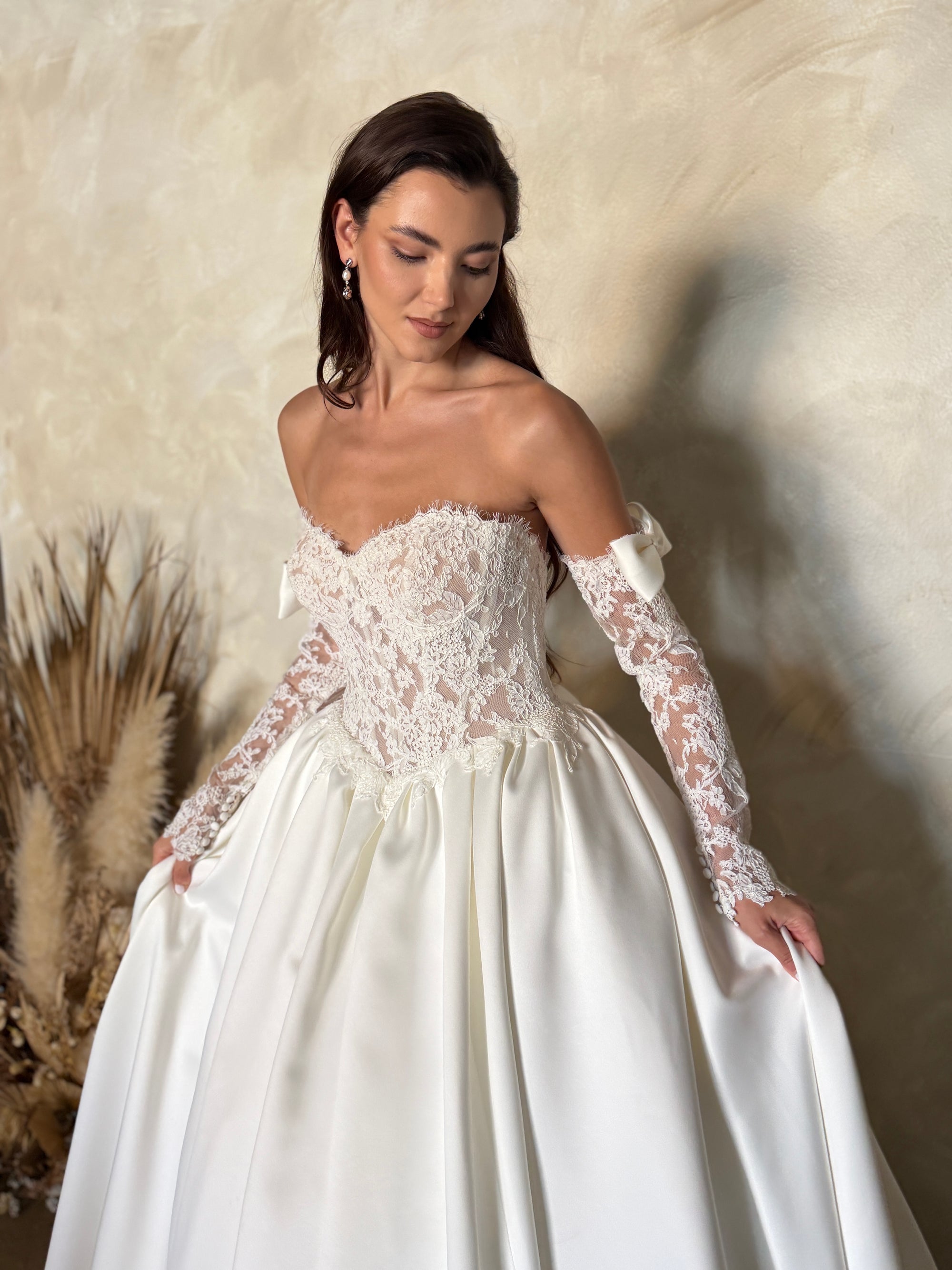 Close-up of the Marcelline ball gown with a French lace corset bodice, sweetheart neckline, and detachable long sleeves with satin bows