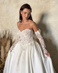 Close-up of the Marcelline ball gown with a French lace corset bodice, sweetheart neckline, and detachable long sleeves with satin bows