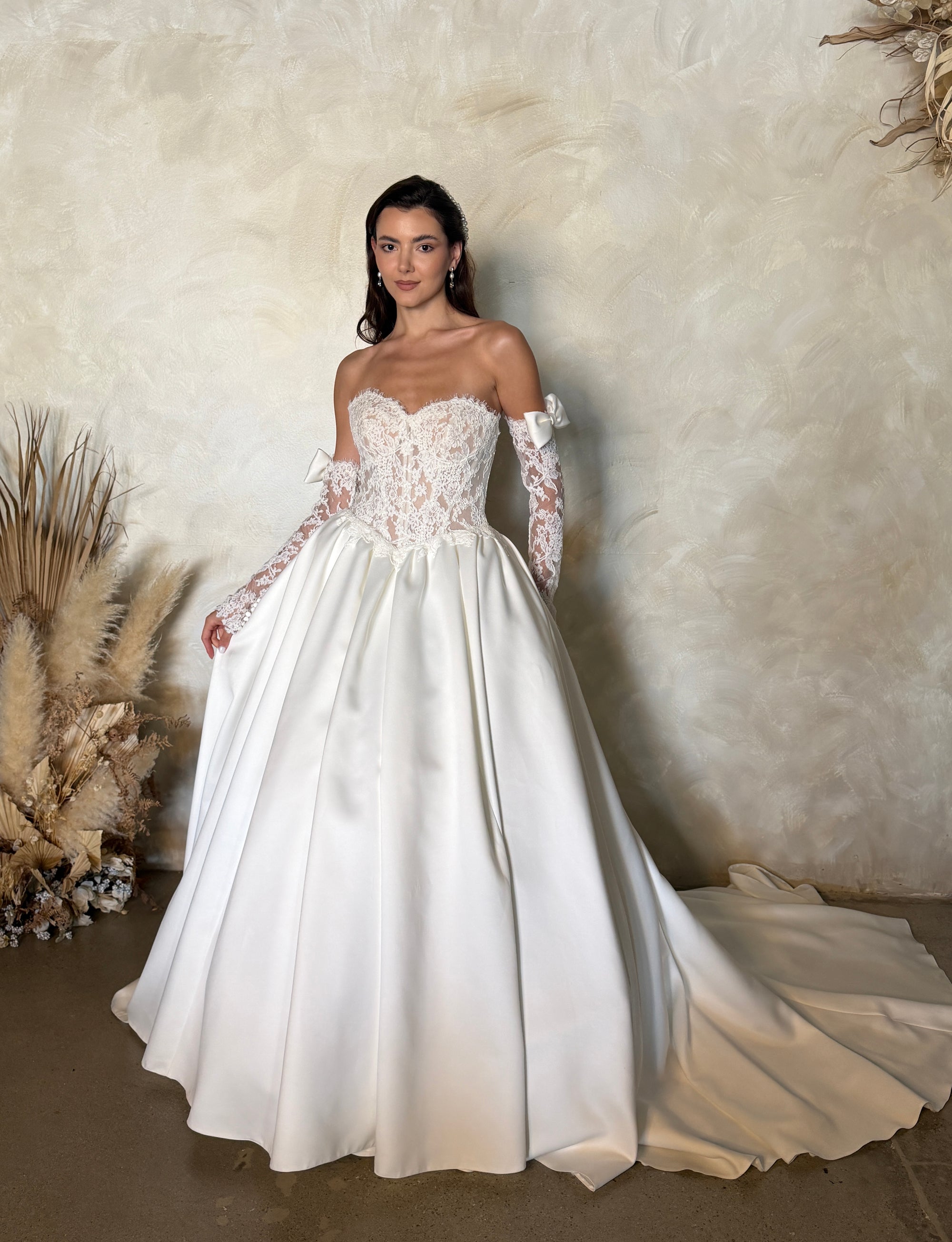 Front view of the Marcelline French lace ball gown with a basque waist, pleated full skirt, and detachable long sleeves