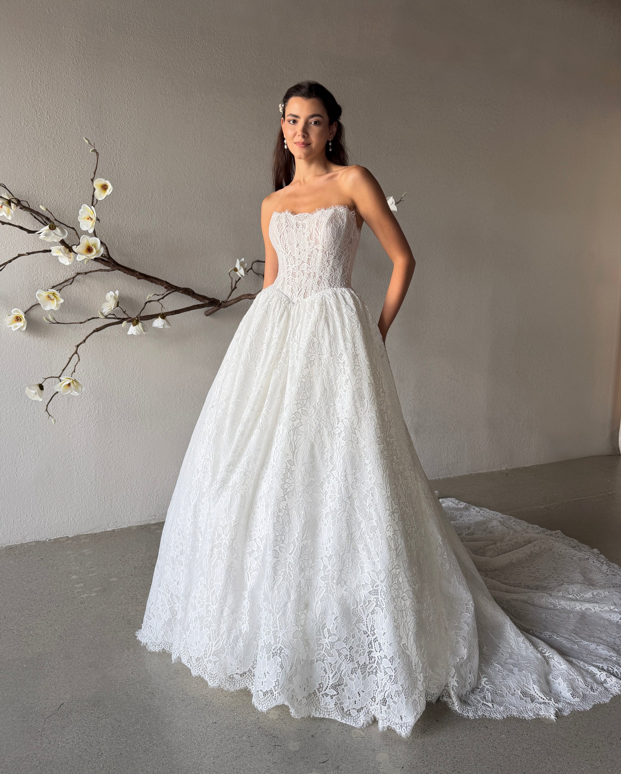 Front view of the Seraphine regal strapless lace ball gown with a basque waist and detachable overskirt