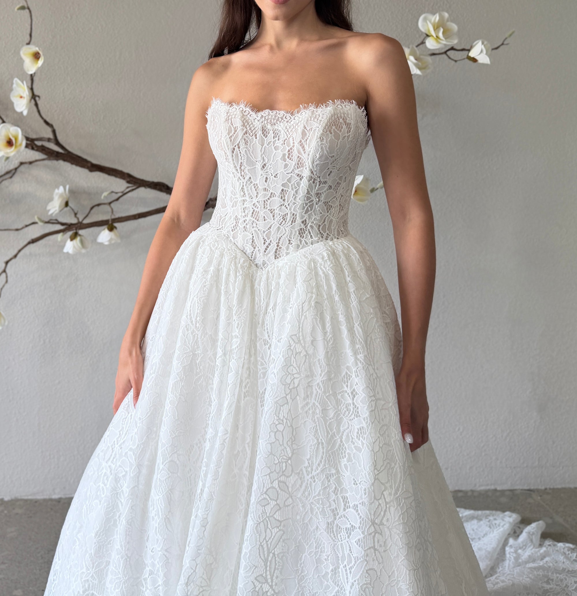 Close-up of the Seraphine strapless lace ball gown bodice with intricate lace, a straight neckline, and a pointed basque waist
