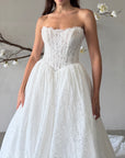 Close-up of the Seraphine strapless lace ball gown bodice with intricate lace, a straight neckline, and a pointed basque waist