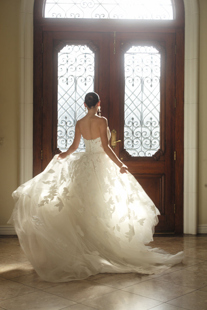 Back view of the Sovereign floral ball gown in motion with a voluminous organza skirt and sweeping train