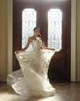 Three-quarter back view of the Sovereign organza ball gown featuring dimensional floral appliqué and a statement train