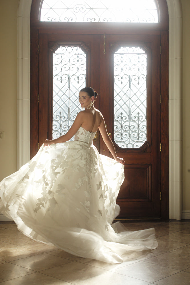Side view of the Sovereign organza ball gown in motion with dimensional floral appliqué and airy volume
