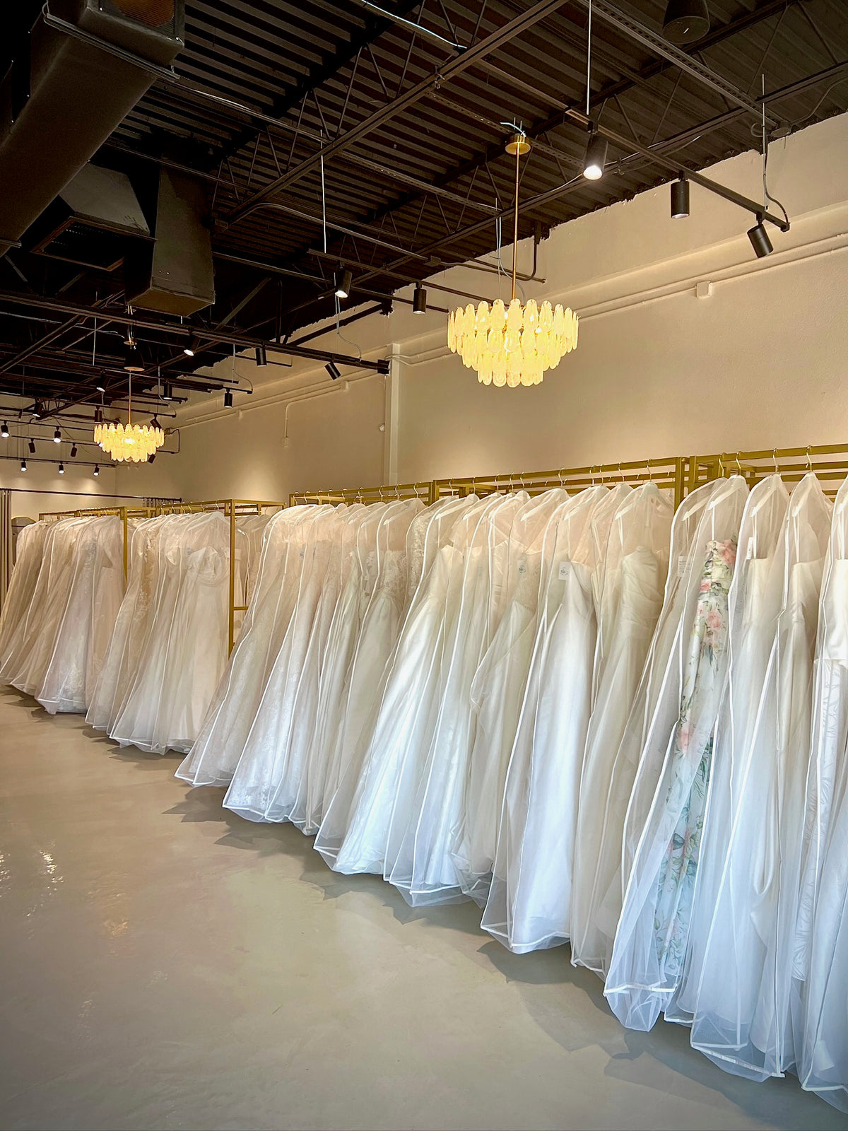 Rows of wedding gowns on gold rails inside Swan Bridal’s San Antonio boutique