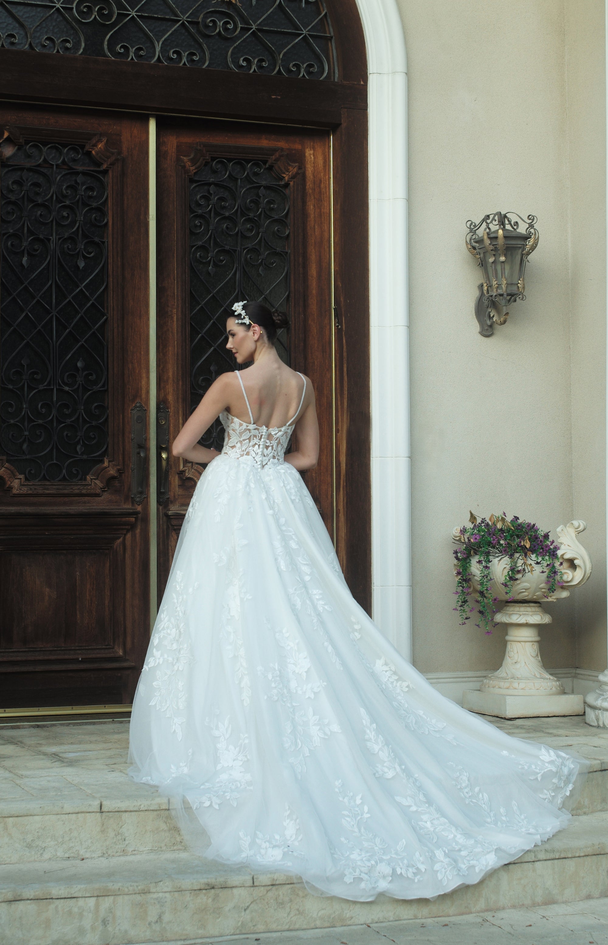 Back view of the Sylvara floral A-line wedding dress with an open illusion lace bodice, spaghetti straps, and a flowing floral train